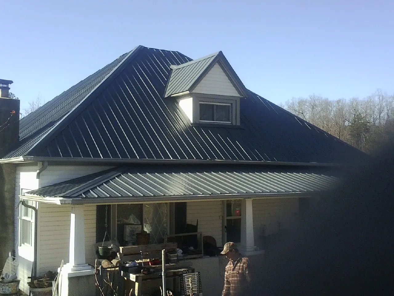 Dark blue standing seam metal roof with a dormer above a front porch in North Haverhill