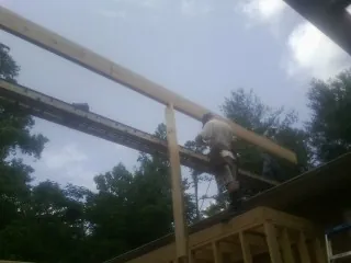 Carpenter setting a ridge beam over a new addition frame — Ice Dam Removal by Roofing Brothers in North Haverhill