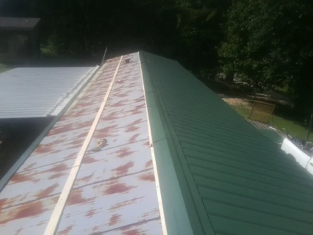 Old rusted panels beside newly installed green metal roofing — Wind Damage Roof Repair by Roofing Brothers in North Haverhill