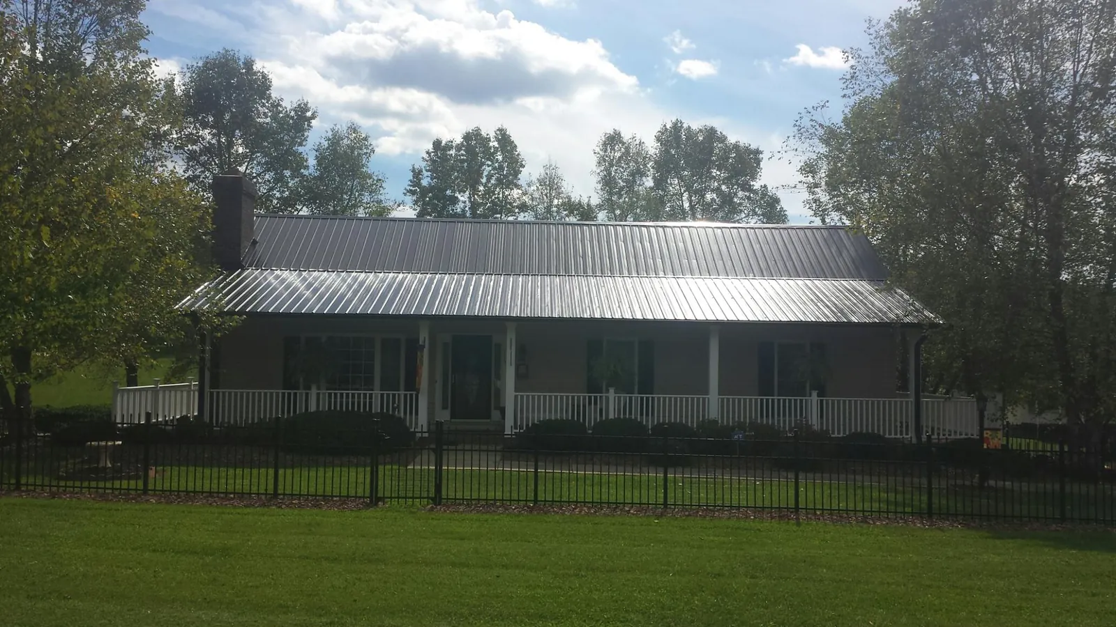 Gray metal roof on a brick ranch with a full width front porch — Gutter Guard Installation work by our crew in North Haverhill